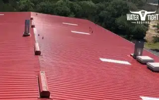Aerial view of a large red commercial roof at sunset, illustrating WaterTight Roofing’s Winter Roof Prep Checklist.