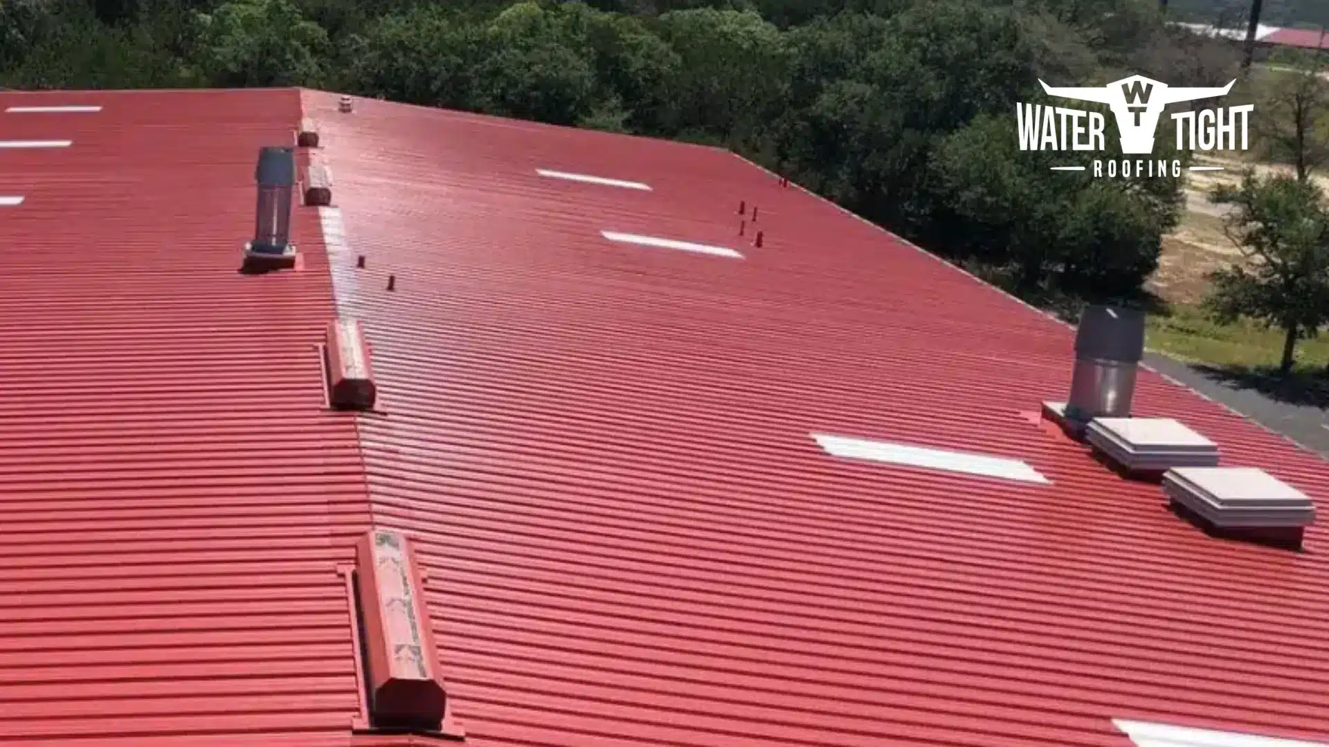 Aerial view of a large red commercial roof at sunset, illustrating WaterTight Roofing’s Winter Roof Prep Checklist.