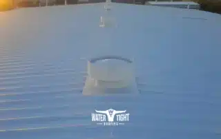 4 Options for Problematic Metal Roofs cover image showing a white commercial metal roof with vents at sunset by WaterTight Roofing
